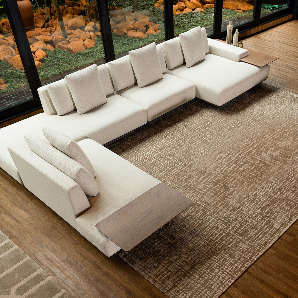 belo e grande sofá em éle cor off white, piso em madeira e sobre um tapete bege