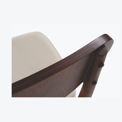 Vista superior do detalhe da Cadeira Dakota, mostrando a união da madeira entre o encosto curvo e o pé traseiro, destacando o acabamento artesanal.