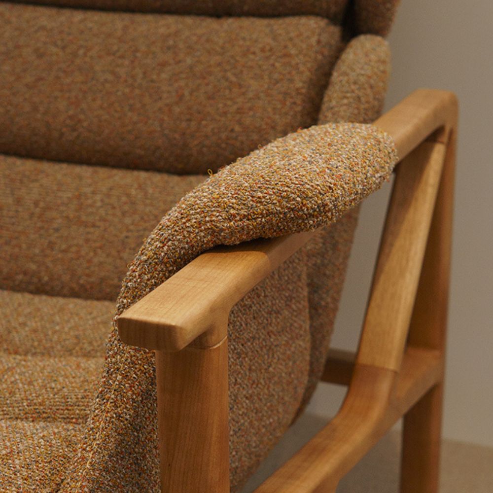 detalhe de um braço de uma poltrona, tecido e braço em madeira exalta a qualidade dos acabamentos.