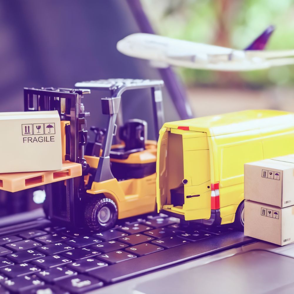 Miniaturas de equipamentos de logística — empilhadeira, van de entrega e caixas — sobre um teclado de notebook, representando operações de envio e transporte no e-commerce.