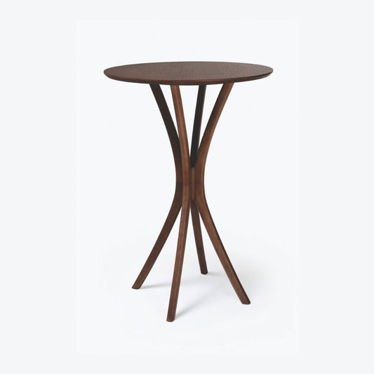 Mesa bistrô Montana em madeira tingida, com tampo redondo e base curva escultural, exibida sobre fundo branco.