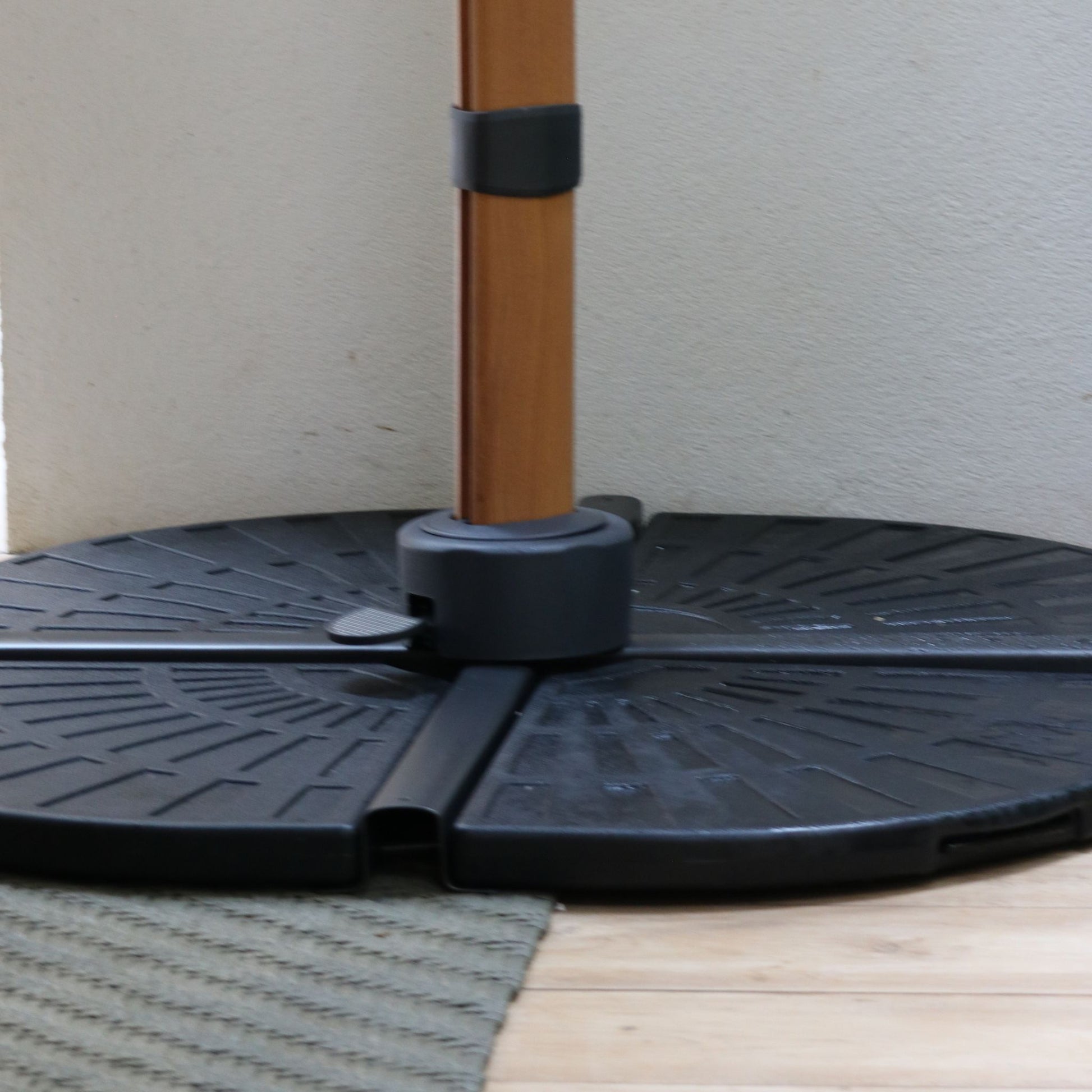 Detalhe da base de contrapeso modular do Ombrelone Manorca, mostrando a haste central encaixada no suporte de fixação preto e o pedal de giro.